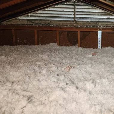 Blown-in fiberglass insulation covering attic floor in Wake County home