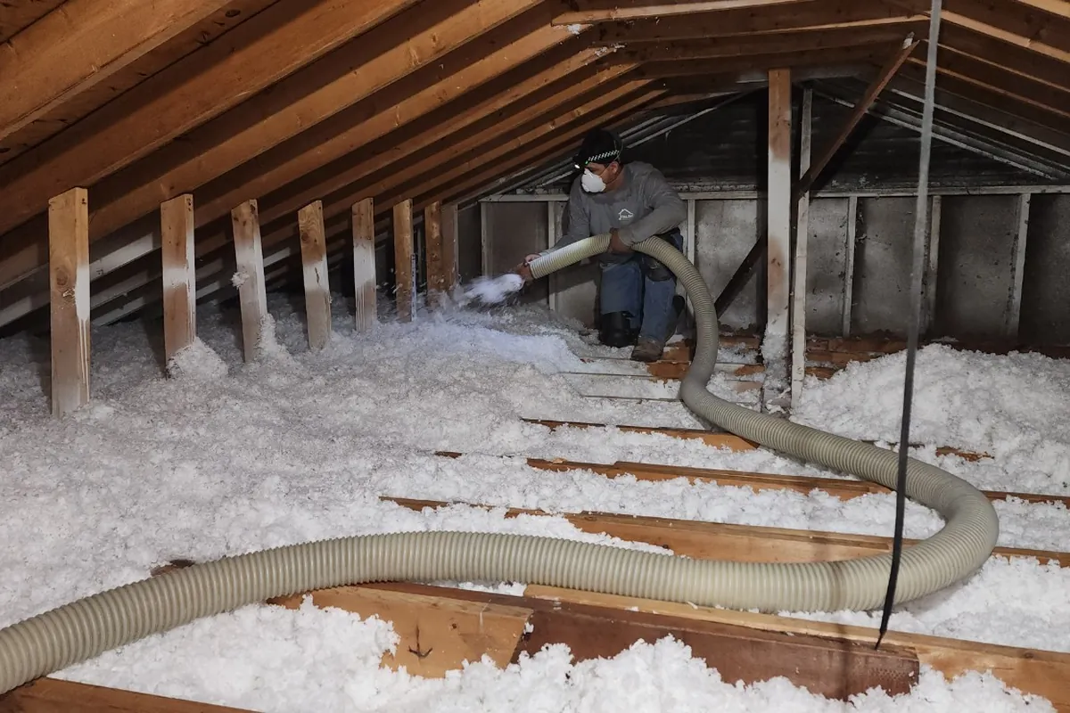 Peak Energy installer blowing loose-fill attic insulation to depth in a Wake County NC home