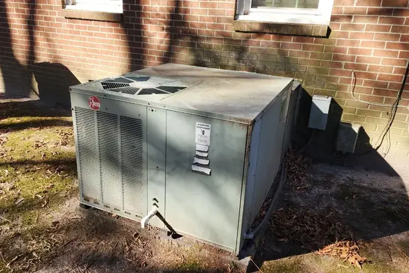 Aging HVAC unit outside a home in Wake County NC showing worn heat pump in need of replacement