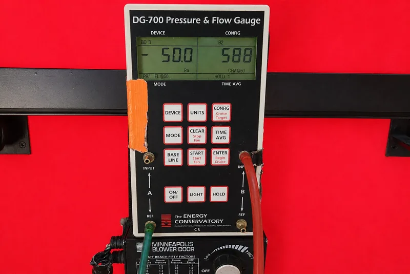 DG-700 pressure and flow gauge on a blower door reading 50 pascals during an air leakage test in a Triangle NC home