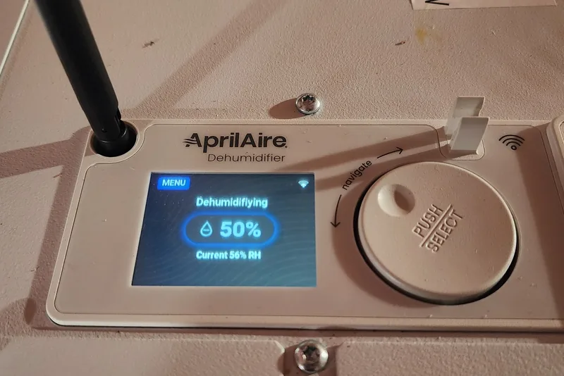 AprilAire WiFi dehumidifier control panel in an NC crawl space set to a 50% relative humidity target, reading 56% current humidity while dehumidifying