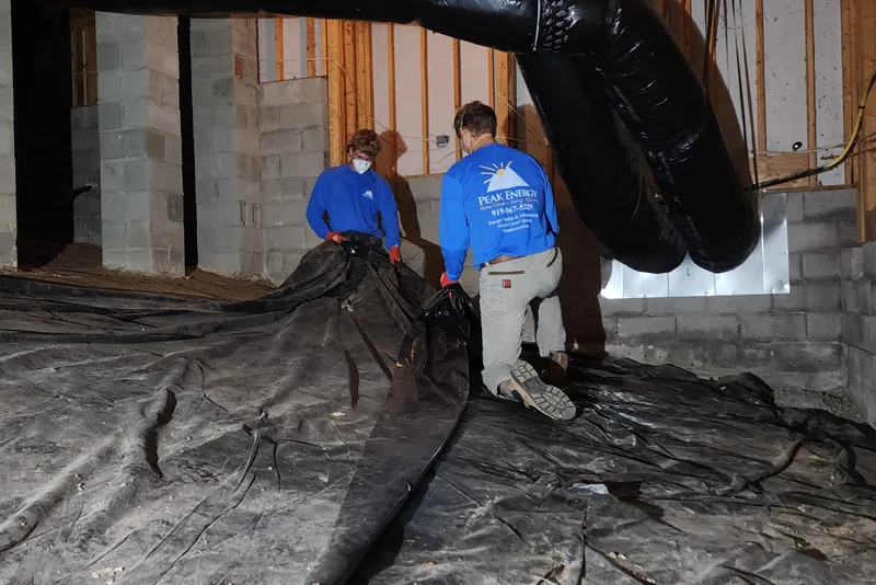 Peak Energy crew pulling up and removing degraded old vapor barrier sheeting from a crawl space floor in NC