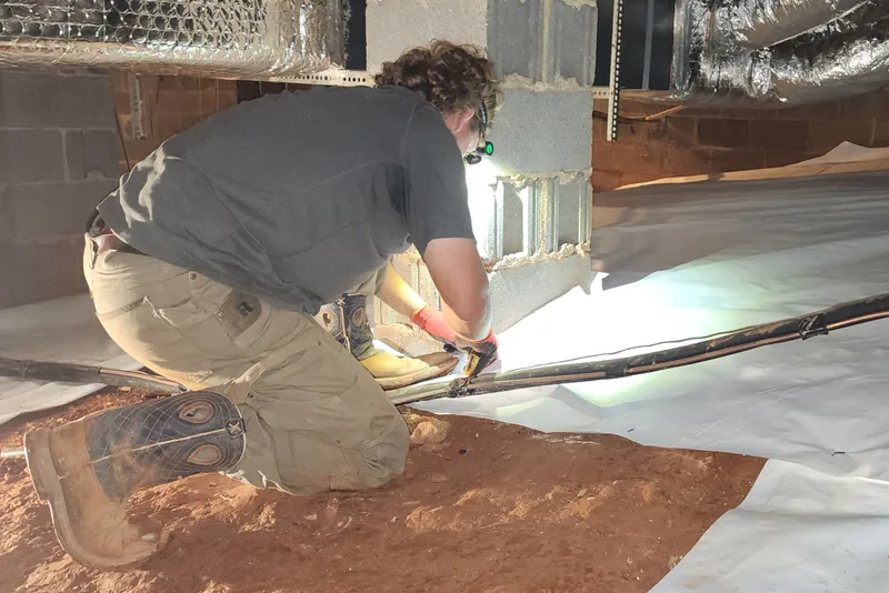 Peak Energy technician sealing the vapor barrier liner around a block pier column in an encapsulated crawl space in NC