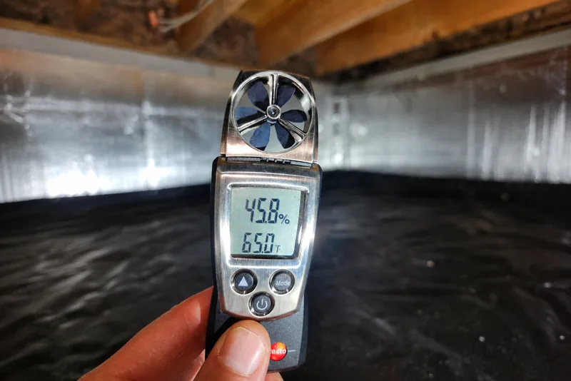Handheld Testo hygrometer reading 45.8% relative humidity in an encapsulated crawl space