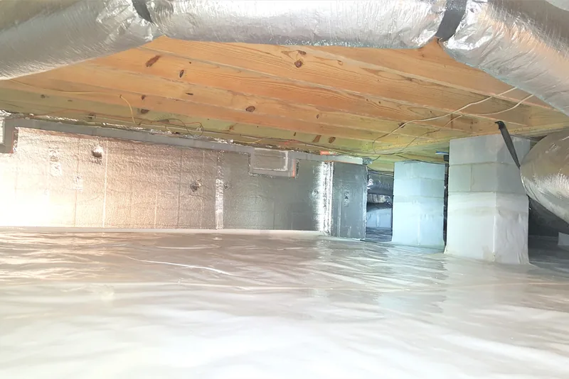 Finished encapsulated crawl space in a Wake County NC home with foil-faced foam board on the foundation walls, wrapped piers, insulated ductwork, and a sealed vapor barrier on the ground