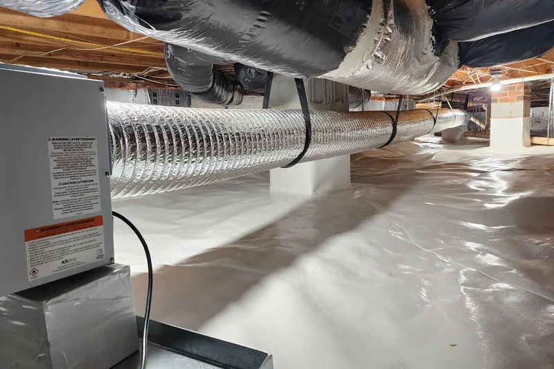 Sealed crawl space in a Wake County NC home with insulated ductwork, a wrapped interior pier, and a heavy white vapor barrier covering the ground