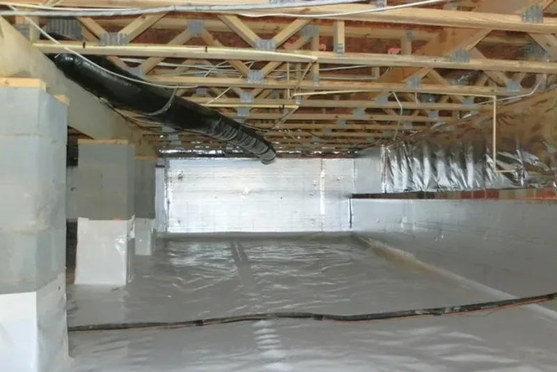 Sealed crawl space with foil-faced rigid foam wall insulation, vapor barrier on the floor and wrapped piers, and conditioned ductwork above — no foundation vents