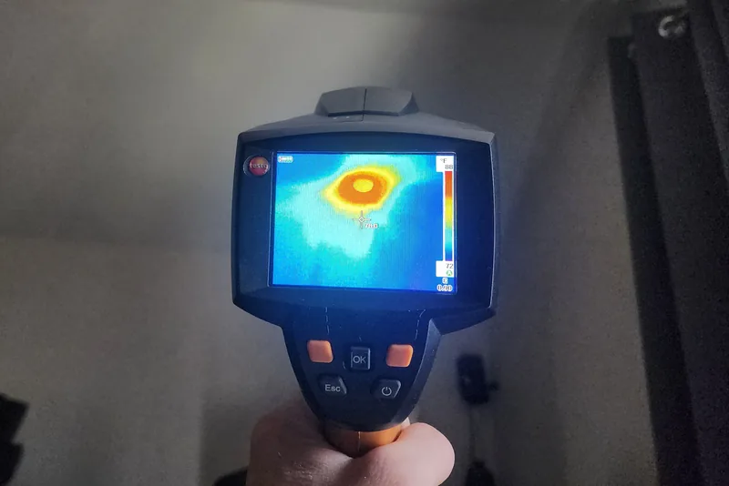 Peak Energy technician using a Testo thermal camera to find a heat leak at a recessed light during a home energy audit in a Triangle NC home
