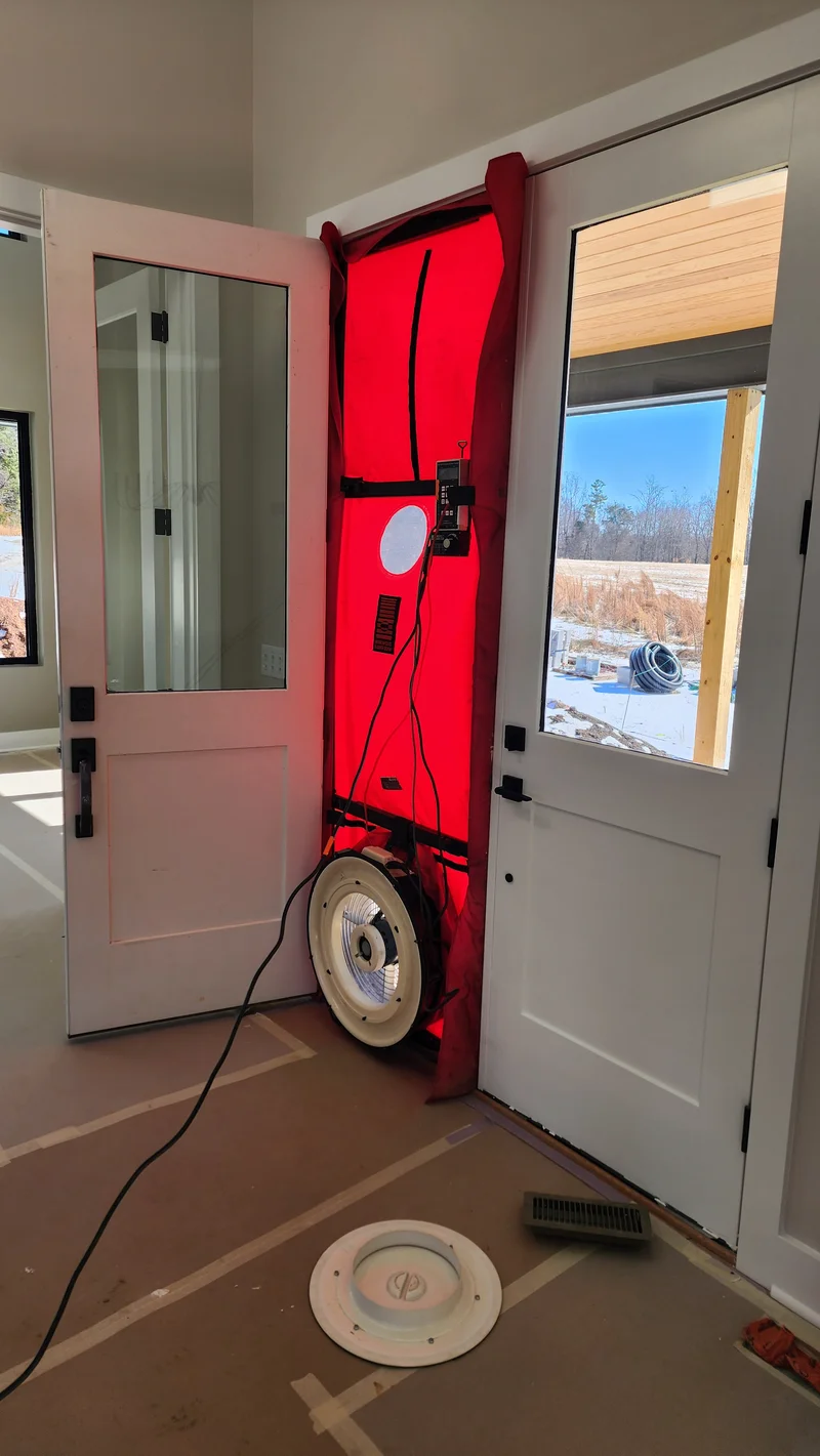 Blower door fan installed in doorway for air leakage testing in Raleigh NC new construction