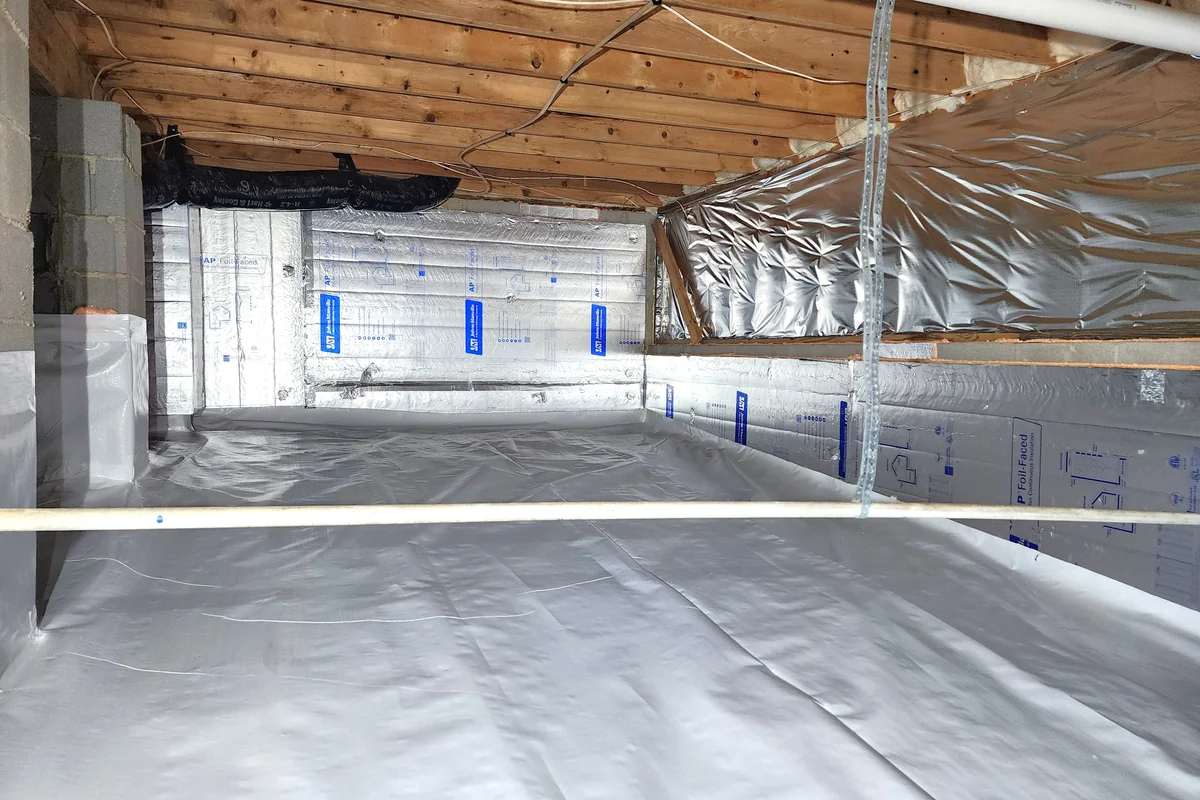 Fully encapsulated crawl space with foil-faced rigid foam wall insulation, sealed rim joist, conditioned ductwork, and continuous vapor barrier across the floor