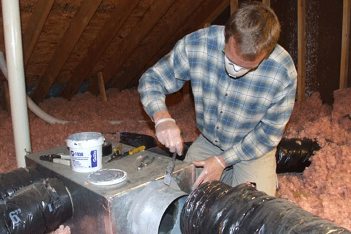 Peak Energy technician sealing ductwork with mastic in an attic in a Triangle NC home