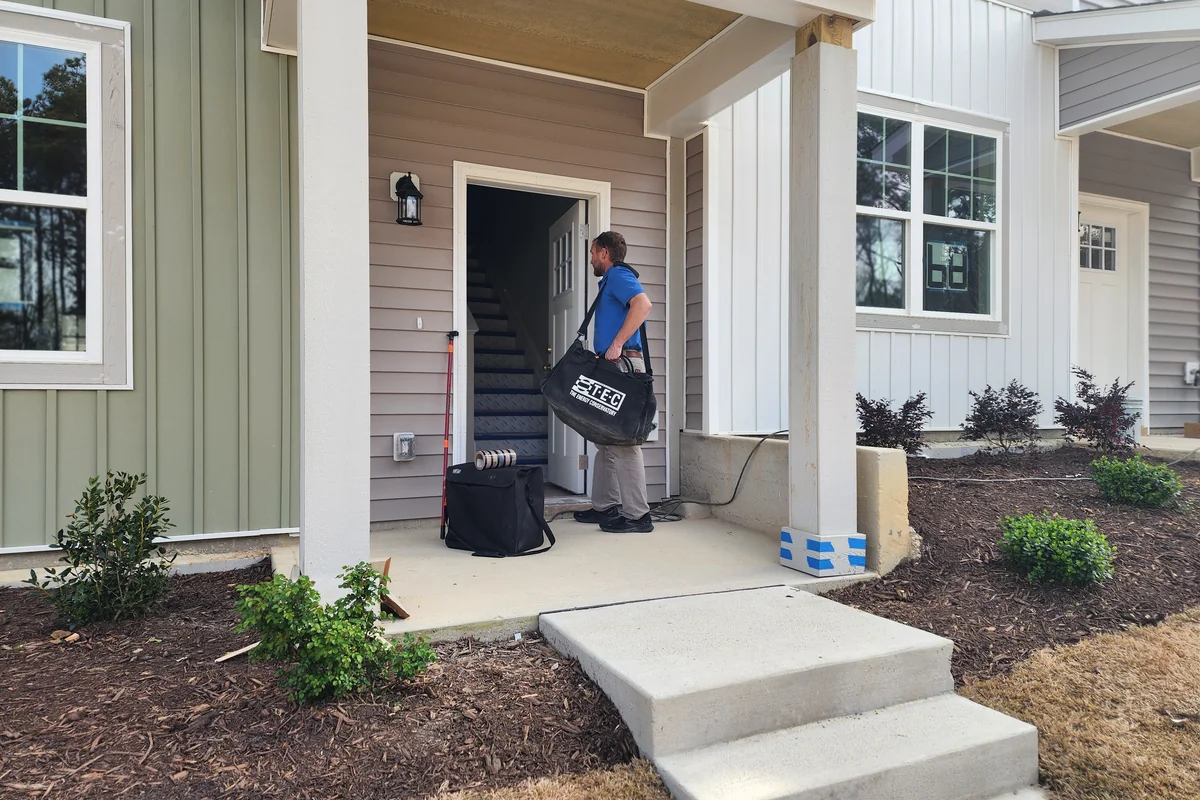 Peak Energy technician arriving on site at a Wake County NC new construction home with calibrated duct blaster equipment, ready for code compliance testing