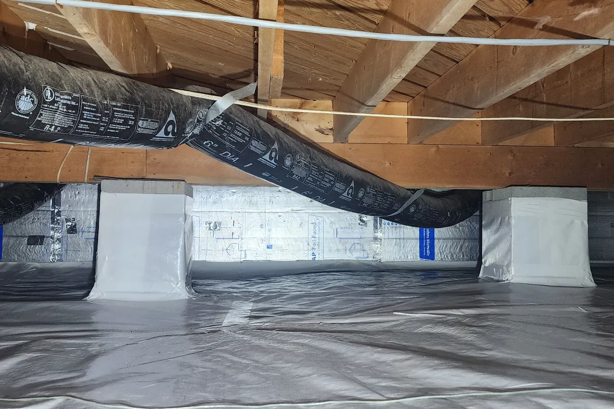 Encapsulated crawl space with a white vapor barrier and insulated ducts in a Triangle NC home