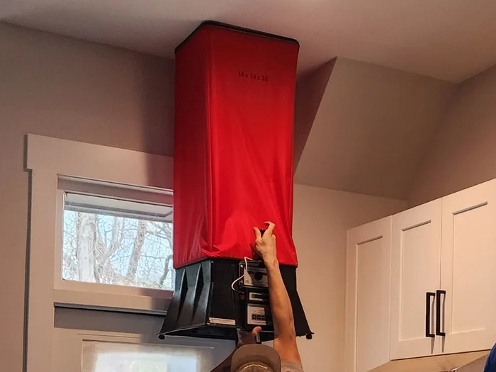 Technician measuring residential range hood exhaust airflow with flow hood in NC